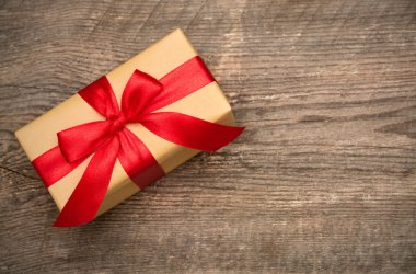 Ahşap arka planda kırmızı kurdeleli hediye kutusu