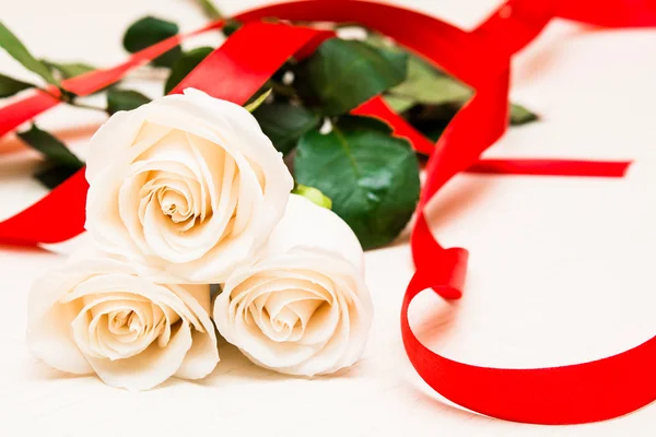 White roses with red ribbon on a light wooden background. Women' — Stok fotoğraf