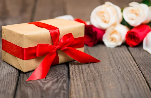 Gift box with blured red and white roses on a dark wooden backgr