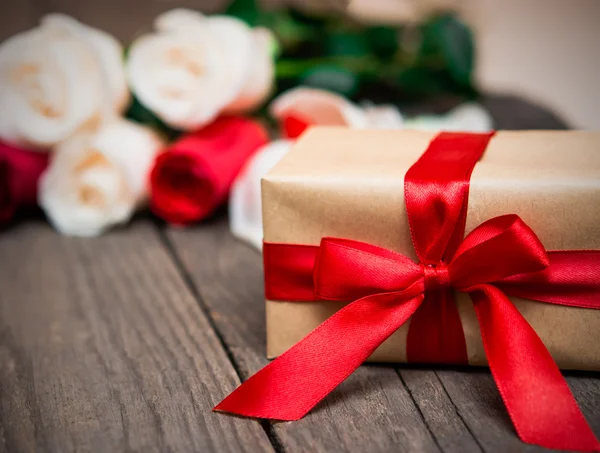 Caja de regalo con rosas rojas y blancas borrosas en un fondo de madera oscura — Foto de Stock