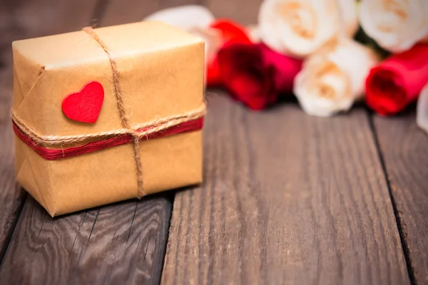 Gift box with blured red and white roses on a dark wooden backgr
