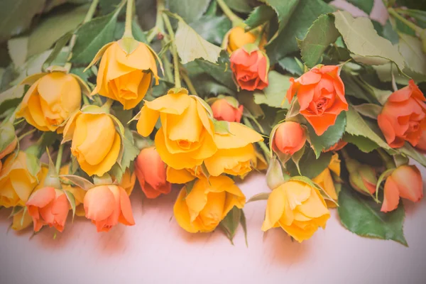 Yellow and orange roses on a light wooden background. Women' s d — Stock Photo, Image