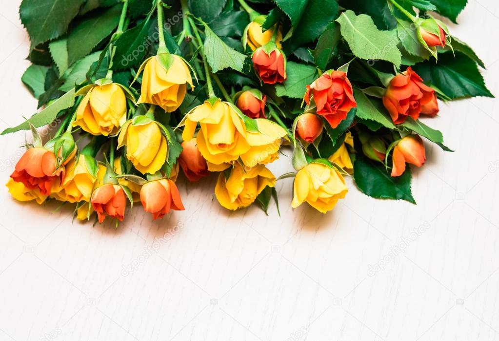 Yellow and orange roses on a light wooden background. Women' s d