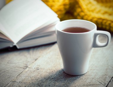 Beyaz fincan çay, kitap ve eşarp eski ahşap masa.
