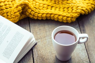 Beyaz fincan çay, kitap ve eşarp eski ahşap masa.