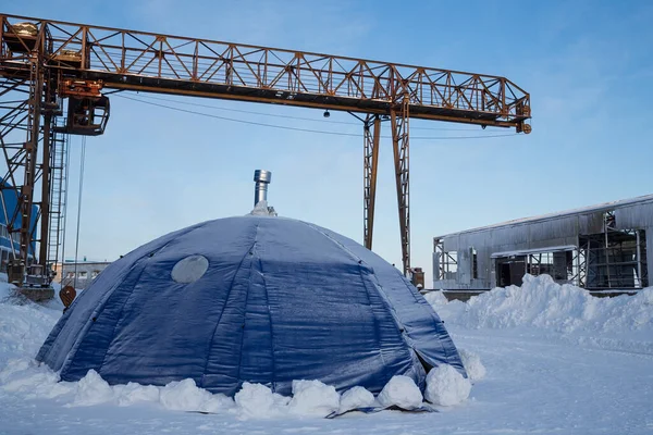Large tent in an industrial area. A modern mobile collapsible house in the form of a traditional home of the indigenous peoples of the far north. Experimental modern home for living in the Arctic.