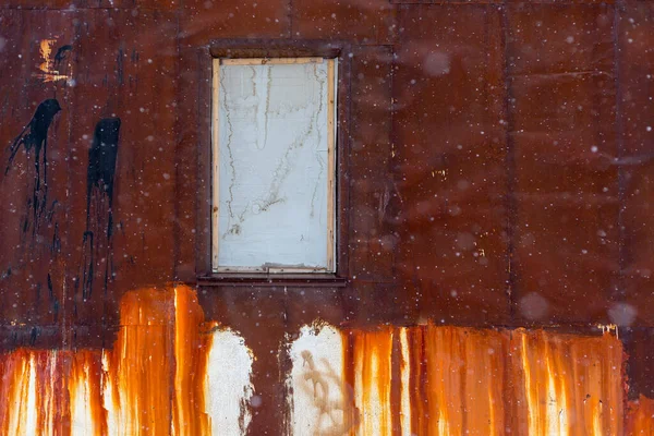 Texture of rusty metal wall with a boarded up window. Old uneven iron surface with stains of paint. Perfect for background and grunge design.
