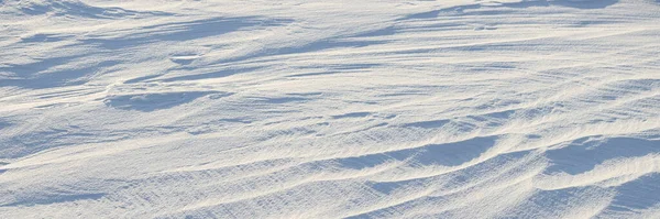 Beautiful winter background with snowy ground. Natural snow texture. Wind sculpted patterns on snow surface. Arctic, Polar region.