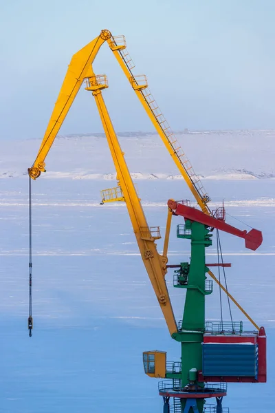 Cargo seaport in the Arctic. Large harbor cranes on a background of ice and snow. Winter industrial landscape. Industry and transport infrastructure in the Far North. Anadyr sea port, Chukotka, Russia