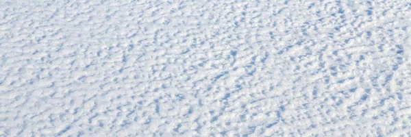 Natural snow texture. The surface of the snow crust. Snowy ground. Winter background with snow patterns. Perfect for Christmas and New Year design. Closeup top view.