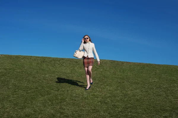 Chica caminar en la hierba con bolsa en la mano — Foto de Stock