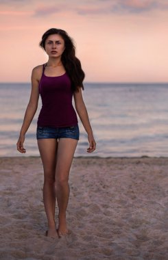 Sahilde duran ve güneşin tadını genç kadın