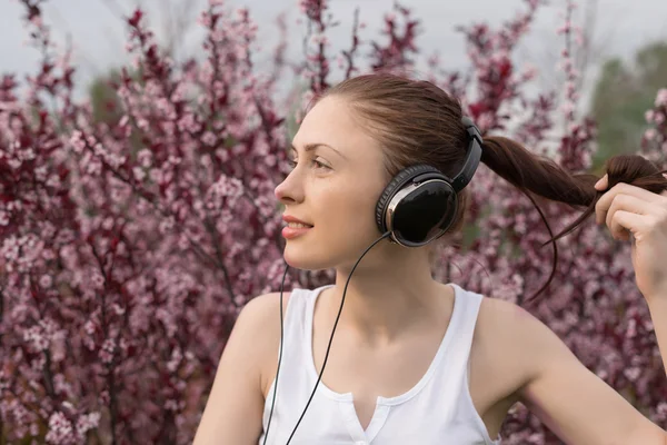 Beautiful girl listening to music on headphones — Stock Photo, Image