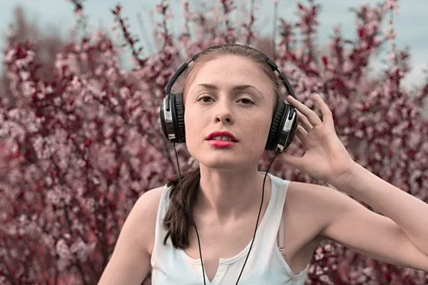 Beautiful girl listening to music on headphones — Stock Photo, Image