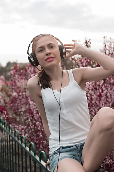 Beautiful girl listening to music on headphones — Stock Photo, Image