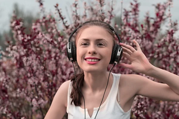 Beautiful girl listening to music on headphones — Stock Photo, Image