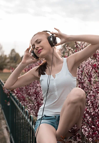 Beautiful girl listening to music on headphones — Stock Photo, Image