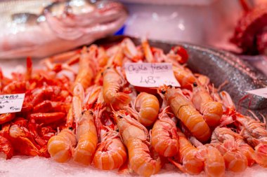 Ön planda karidesli taze kerevit ve arka planda hake. Valencia 'da arka planda fiyatı olan bir balık pazarına odaklanmışlar.