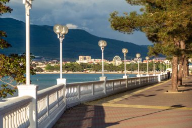 Beyaz bir balyoz, gün batımında setin üzerinde güzel gölgeler bırakır. Arka planda dağlar ve deniz var. Toprak seti mesafeye gidiyor..