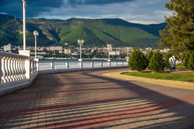 Beyaz bir balyoz, gün batımında setin üzerinde güzel gölgeler bırakır. Arka planda dağlar ve deniz var. Toprak seti mesafeye gidiyor..