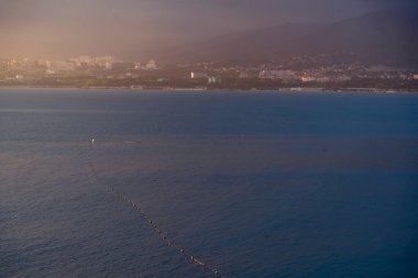Balık ağı gün batımında mavi denize açılır. Dağlar ve arka plandaki evler. Gün batımı.