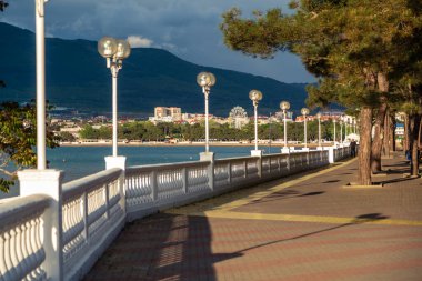Beyaz bir balyoz, gün batımında setin üzerinde güzel gölgeler bırakır. Arka planda dağlar ve deniz var. Toprak seti mesafeye gidiyor..
