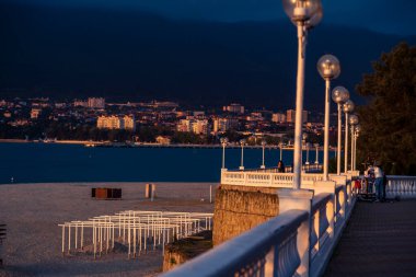 Gün batımında Balustrade 'lı toprak seti. Sahil manzaralı, körfez ve dağlar. Balüstrad, batan güneş tarafından güzelce aydınlatılır. Arka planda karanlık dağlar.