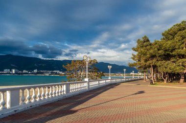 Beyaz bir balyoz, gün batımında setin üzerinde güzel gölgeler bırakır. Arka planda dağlar ve deniz var. Toprak seti mesafeye gidiyor..