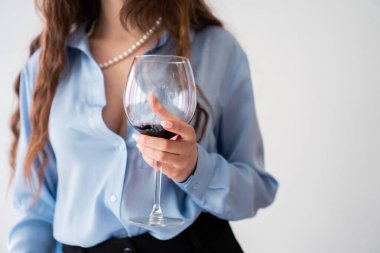 Ofis kızı mavi gömlekli ve inci kolyeli, bir bardak şaraplı.