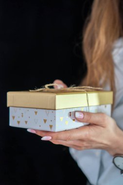 Manikürlü kız elinde altın bir hediye tutuyor