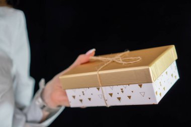 Manikürlü kız elinde altın bir hediye tutuyor