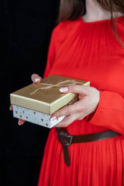 Kırmızı elbiseli, uzun saçlı, hediye kutusu olan bir kız.