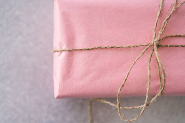 розовый подарок в верёвке на белом фоне