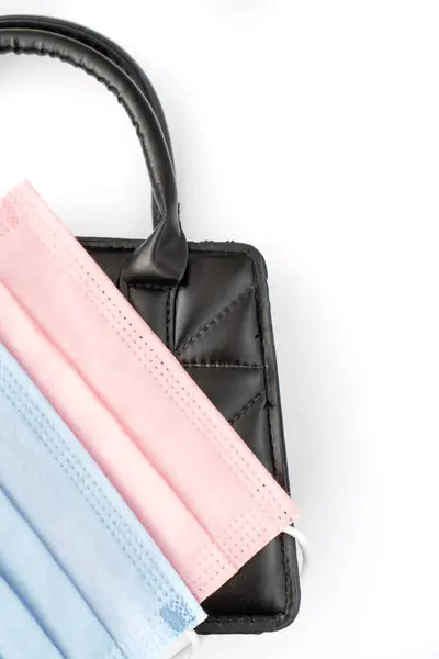 黒のエレガントなハンドバッグにピンクと青の保護マスク — ストック写真