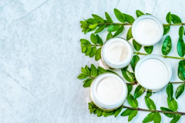 Kozmetik olarak düz: lezzetli yeşillik dalları üzerinde altın renginde cilt bakım kavanozları