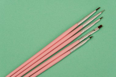 Kozmetik düz yatak: yeşil arkaplanda pembe makyaj fırçaları
