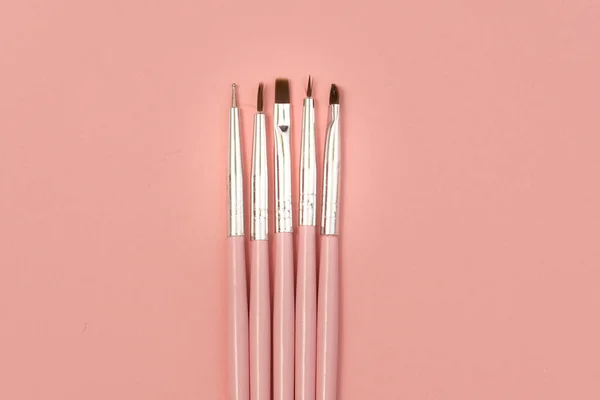cosmetic flat lay: pink makeup brushes on pink background