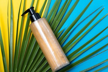 Açık mavi ve mavi arkaplanda yeşil palmiye yapraklı sahte bronzlaşma kremi