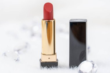 Beyaz kabarık arkaplanda minimal tasarımı olan kırmızı ruj ve elmas şeklinde cam taşlar.