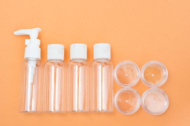 Turuncu arka planda kozmetik ürünler için küçük seyahat şişeleri ve kavanozlarının bileşimi