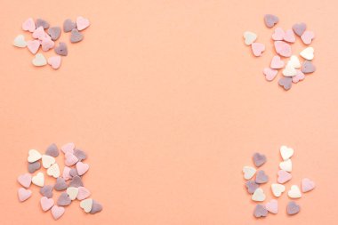 Beyaz, mor ve pembe renkte kalp şeklinde tatlılar serpiyorlar.