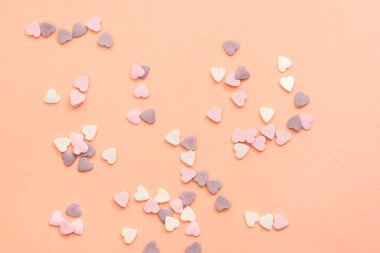 Beyaz, mor ve pembe renkte kalp şeklinde tatlılar serpiyorlar.