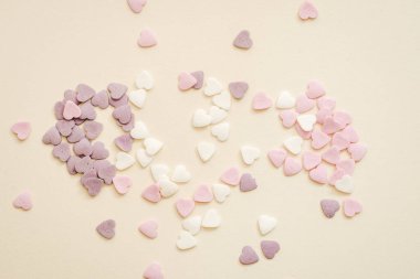 Beyaz, mor ve pembe renkte kalp şeklinde tatlılar serpiyorlar.