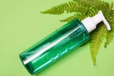 Yeşil arka planda yüz bakımı kozmetik ürünleri ve yeşil yapraklı düz kompozisyon