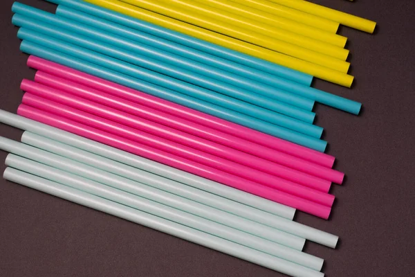 colourful cocktails straw for drinks in pink, yellow, blue colours on a dark background