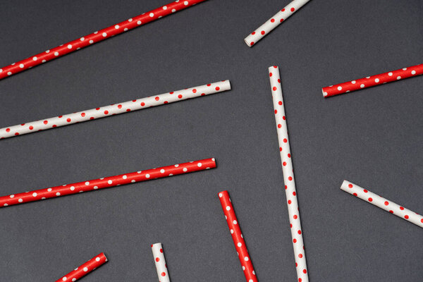 переработанная бумажная солома для напитков красного и белого цветов на темном фоне