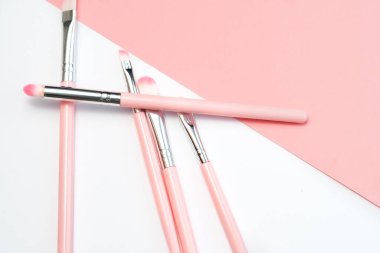 Profesyonel makyaj fırçaları seti. Beyaz ve pembe arka planda gümüş ve pembe renkte süslü pembe makyaj fırçaları.
