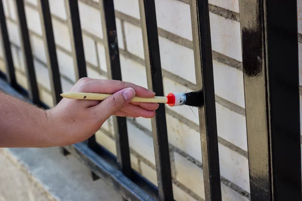 Main avec peinture au pinceau clôture métallique — Photo