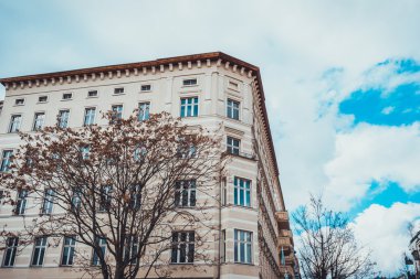 Mavi gökyüzü ve arkasında bulutlar olan güzel beyaz bir ev.