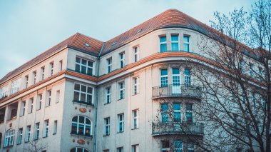 Düşük Açı Dış Görünümü Modern Lüks Low Rise Apartmanı Sunset 'te, Sıcak Güneş Işığıyla aydınlatılan ve Çerçevelenen Çıplak Ağaçlar Sonbaharın Sonlarında